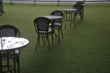 Sandalye ve masa bahçede suni çimlerin üzerine kurulmuş.