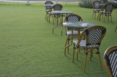 Sandalye ve masa bahçede suni çimlerin üzerine kurulmuş.