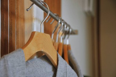Modern ahşap gardırop, korkuluklarda asılı giysiler, dolapta yürüyüş, farklı renkte moda kıyafetleri ahşap askılarda.