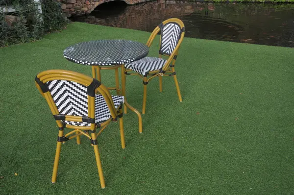 Sandalye ve masa bahçede suni çimlerin üzerine kurulmuş.