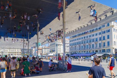 Marsilya, FRANCE - 2 AĞUSTOS 2022: şehrin eski limanında bir ayna tepe örtüsü altında insanlar. Antik çağlardan beri şehrin doğal limanı konumundadır ve şu anda Marsilya 'nın en popüler yeridir. 2013 'te daha çok yayaya çıktı.. 