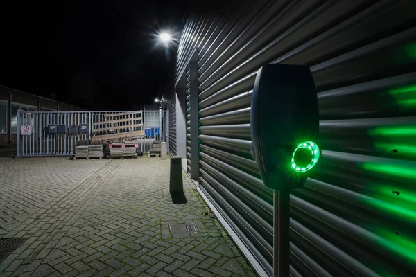 外面的一个荒凉的仓库在夜间与电动汽车充电器在前面 — 图库照片