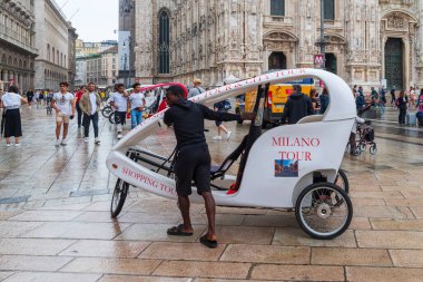 MILAN, ITALY - 4 AĞUSTOS 2021: Sokak satıcısı ünlü duomo katedralinin önünde bisiklet taksisine binmeyi teklif ediyor.