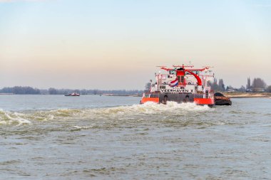 NIJMEGEN, NETHERLANDS - 9 Mart 2024: Muazzam Hollanda mavnası Waal nehrinde bir yığın siyah kumla geziniyor