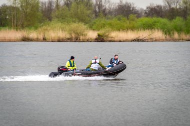 KAMPEN, NETHERLANDS - 30 Mart 2024: Hollanda 'daki IJssel nehri üzerinde hız yapan üç kişi ile motorlu tekne