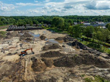 OLDENZAAL, NETHERLANDS - 14 Temmuz 2024: Boş bir inşaat sahasındaki kazıcıya gökyüzü manzarası