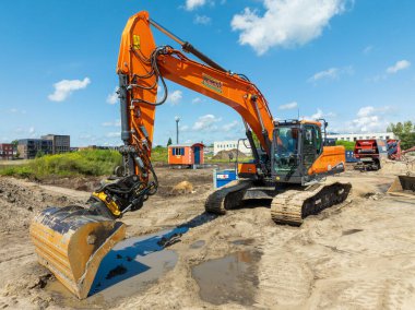 OLDENZAAL, NETHERLANDS - 14 Temmuz 2024: Boş bir inşaat sahasının kazıcısı