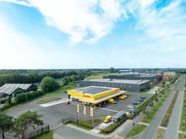 ALMELO, NETHERLANDS - 31 Ağustos 2024: Çatıda bazı güneş panelleri olan bir DHL servis noktasının havadan görünüşü