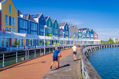 HOUTEN, NETHERLANDS - 7 Eylül 2024: Göl kenarındaki renkli gökkuşağı evlerinin önünde oynayan çocuklar.