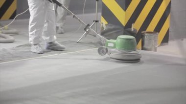 Processing a concrete floor with a grinder close-up. Grinding concrete floor large plan. Construction site equipment close-up.