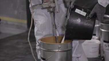 The builder stirs the building mixture in a bucket. A construction worker stirs cement mixture in a construction bucket. Builder prepares material for construction