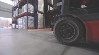 Depodan geçen bir forkliftin yakın çekimi. Forklift hareket halinde, yakın plan. Forklift tekerlekleri yakın çekim.