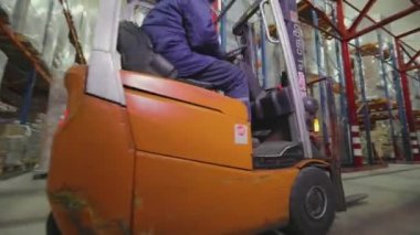 Forklift kullanan bir işçi bir depoda çalışacaktır. Büyük, modern bir depo. Depo çalışması.