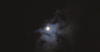 Full moon behind clouds. Full moon. The movement of the clouds against the background of the full moon.