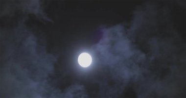 Full moon behind clouds. Full moon. The movement of the clouds against the background of the full moon.