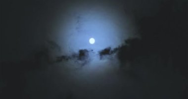 Full moon behind clouds. Full moon. The movement of the clouds against the background of the full moon.