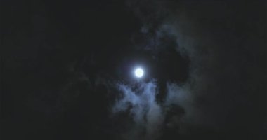 Full moon behind clouds. Full moon. The movement of the clouds against the background of the full moon.
