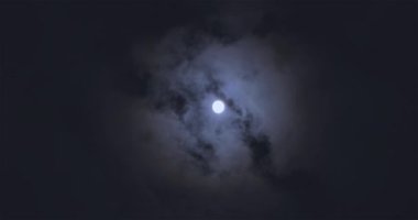 Full moon behind clouds. Full moon. The movement of the clouds against the background of the full moon.