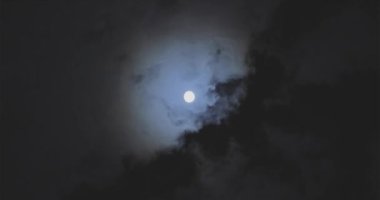 Full moon behind clouds. Full moon. The movement of the clouds against the background of the full moon.