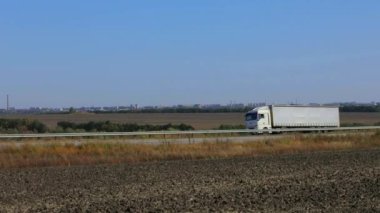 Kamyon güneşli havada otoyol boyunca sürer. Kamyon modern bir yolda gidiyor. Pistte kamyon var.