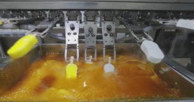 Ice cream is dipped into a container with fruit glaze. Colorful bright ice cream on the conveyor. Ice cream production.
