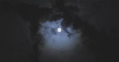 Full moon behind clouds. Full moon. The movement of the clouds against the background of the full moon.