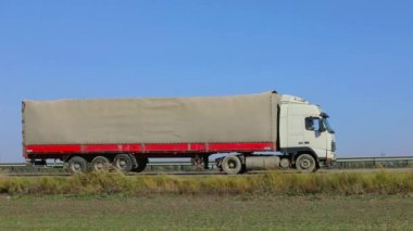 Kamyon güneşli havada otoyol boyunca sürer. Kamyon modern bir yolda gidiyor. Pistte kamyon var.