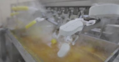 Ice cream is dipped into a container with fruit glaze. Colorful bright ice cream on the conveyor. Ice cream production.