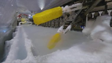 Ice cream is dipped into a container with fruit glaze. Colorful bright ice cream on the conveyor. Ice cream production.