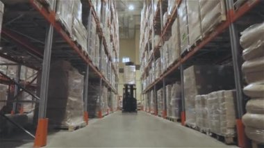 A forklift is driving through a large warehouse. Moving through a modern warehouse. Large modern warehouse in the factory.