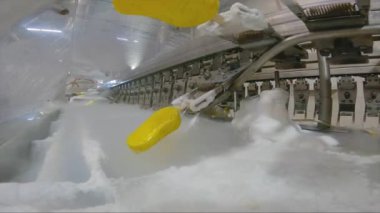 Ice cream is dipped into a container with fruit glaze. Colorful bright ice cream on the conveyor. Ice cream production.