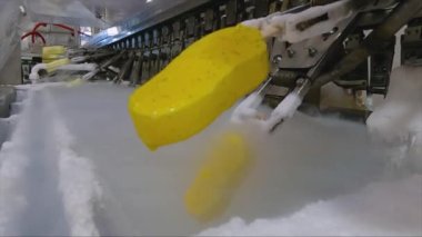 Ice cream is dipped into a container with fruit glaze. Colorful bright ice cream on the conveyor. Ice cream production.