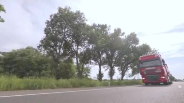 Kamyonlar yol boyunca gidiyor. Tank kamyonu olan bir kamyon otoyol boyunca yaklaşır. Tehlikeli malların nakliyesi.