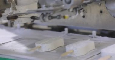 Apparatus for sorting ice cream. Ice cream dosing machine on a conveyor line. Automated conveyor line. Food production.