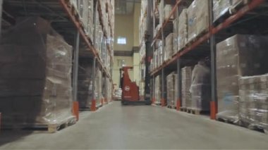 A forklift is driving through a large warehouse. Moving through a modern warehouse. Large modern warehouse in the factory.