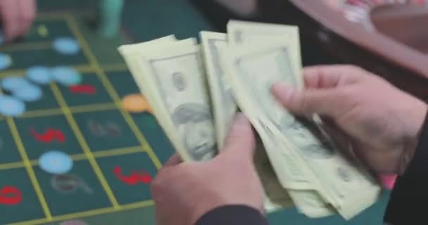 玩家数美元 赌场里的玩家数钱 数着赌场赢的钱一个男人把美元算作特写镜头 — 图库视频影像