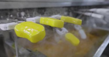 Ice cream is dipped into a container with fruit glaze. Colorful bright ice cream on the conveyor. Ice cream production.