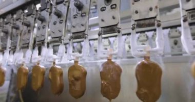 Ice cream in chocolate on the conveyor line. Production of ice cream on a stick. Automated conveyor line.