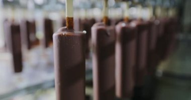 The chocolate drips nicely off the ice cream. Chocolate dripping from ice cream slow motion. Ice cream is dipped in chocolate at the factory.