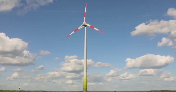 Tuuliturbiini Vihreällä Pellolla Sinistä Taivasta Vasten Pilvillä Tuuligeneraattori Kentällä Tuuliturbiinien — kuvapankkivideo