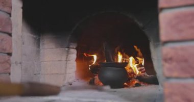 Yanan bir odun fırınında kazan. Yanan bir odun sobasına demir kazanı dök. Eski odun sobası. Yemek pişiyor ama fırında yanıyor..