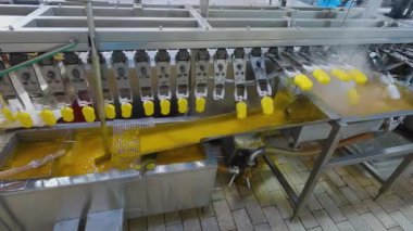 Ice cream is dipped into a container with fruit glaze. Colorful bright ice cream on the conveyor. Ice cream production.