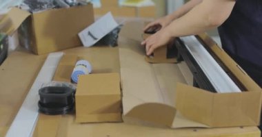 Kadın paketleyici ürünü bir kutuya koyar. Malları bir kutuya koymak. Paketçi fabrikada çalışıyor..