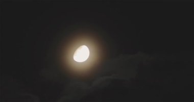 Gece gökyüzündeki parlak ay, yüzen bulutların arka planına karşı. Dolunay gökyüzünde yüzen bulutların arka planına karşı. Gece gökyüzünde ay ve bulutlar