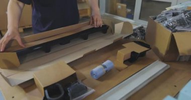 Kadın paketleyici ürünü bir kutuya koyar. Malları bir kutuya koymak. Paketçi fabrikada çalışıyor..