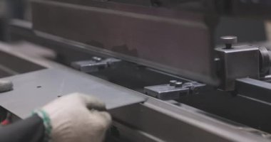 Hidrolik levha metal bükme makinesi. Bir işçi bir makinede metal bir parçayı büker.