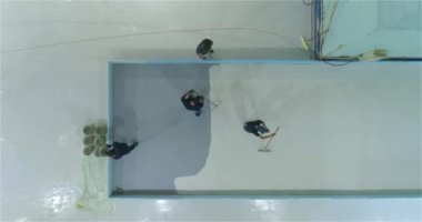 İnşaatçılar endüstriyel bir binanın zeminine polimer kaplama uyguluyorlar. Profesyonel bir ekip fabrika atölyesinde polimer döşeme yapıyor..