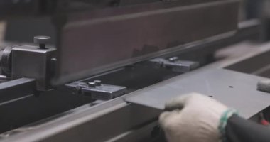 Hidrolik levha metal bükme makinesi. Bir işçi bir makinede metal bir parçayı büker.