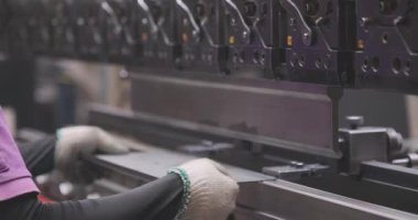 Hidrolik levha metal bükme makinesi. Bir işçi bir makinede metal bir parçayı büker.
