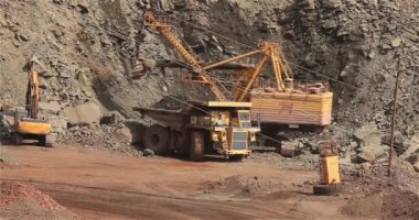 Büyük bir maden kazıcısı bir maden kamyonunu demir madenine yüklüyor.